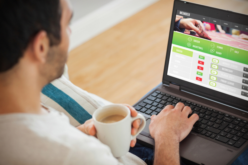 Man using laptop against gambling app screen