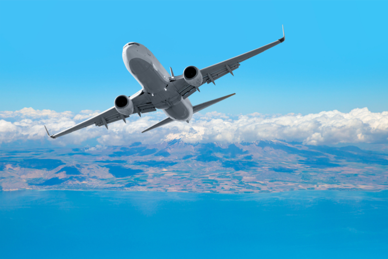 Passenger plane flying above sea against sky background