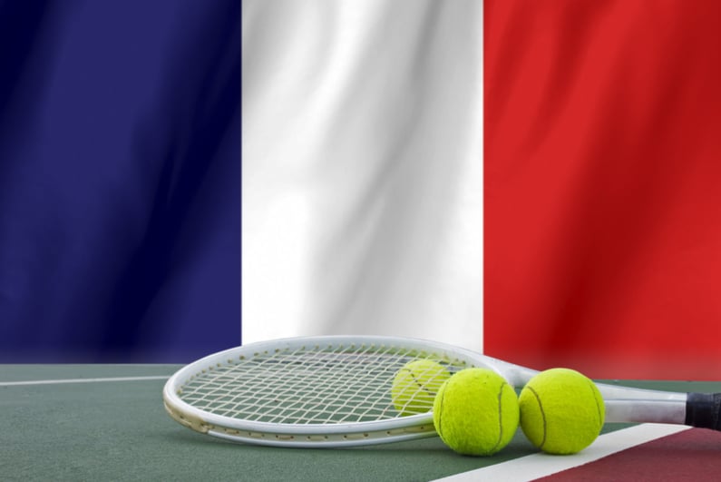 Tennis rackets and balls with French flag in background