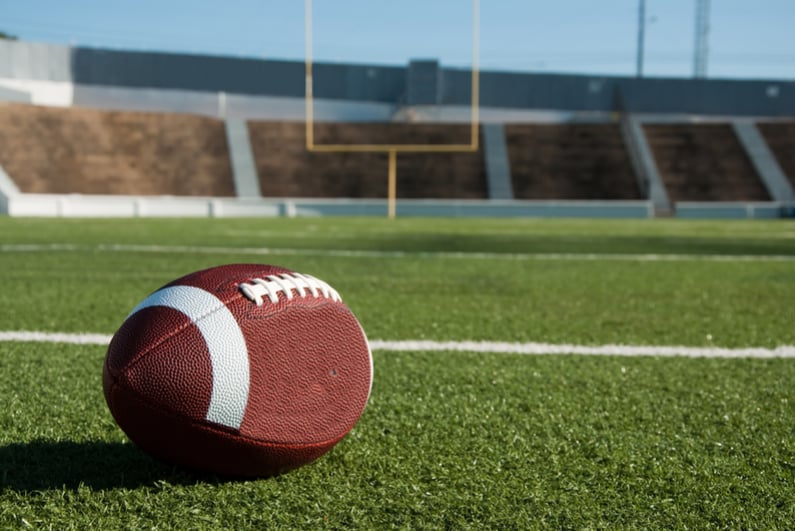 American football on field with goal post in background