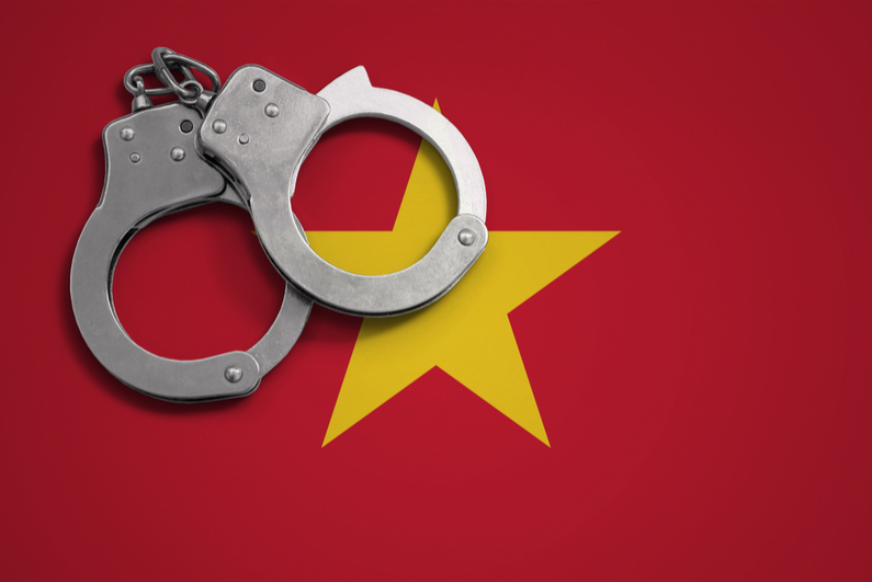 Police handcuffs on flag of Vietnam