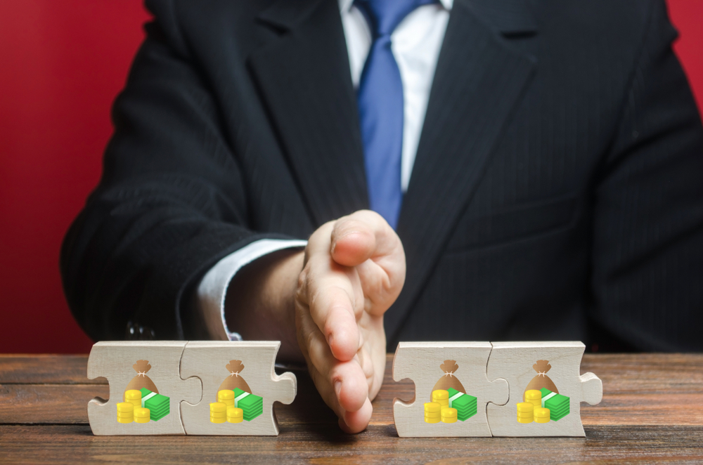 A businessman splitting bricks with money symbols